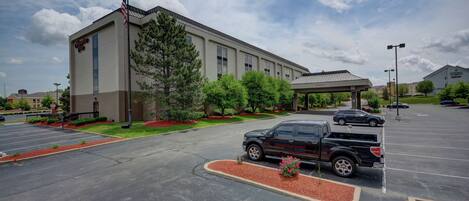 A hotel with a parking lot, a covered outdoor area, and a flagpole.