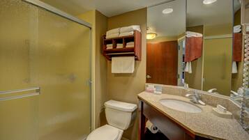 A bathroom with a shower, toilet, sink, and a mirror.