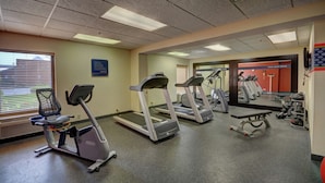Une salle de sport équipée de tapis de course, d’un banc et de matériel d’exercice.
