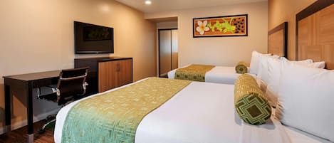 Habitación de hotel con dos camas, un escritorio, una silla y un televisor.