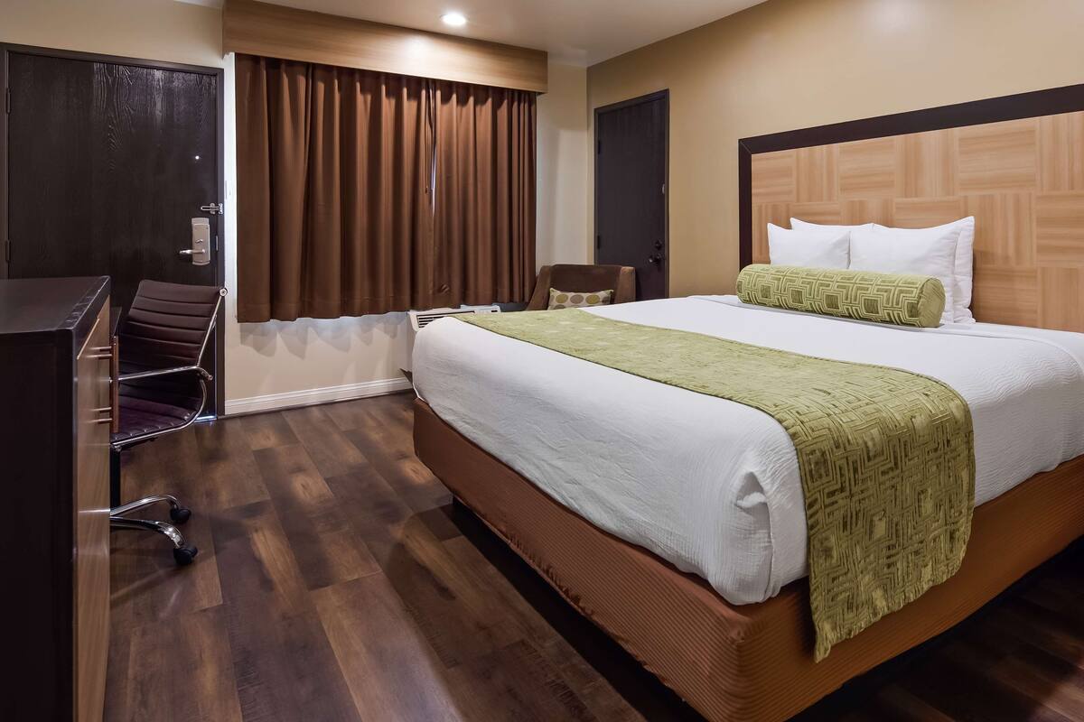 Une chambre d’hôtel avec un grand lit, un bureau et une chaise.