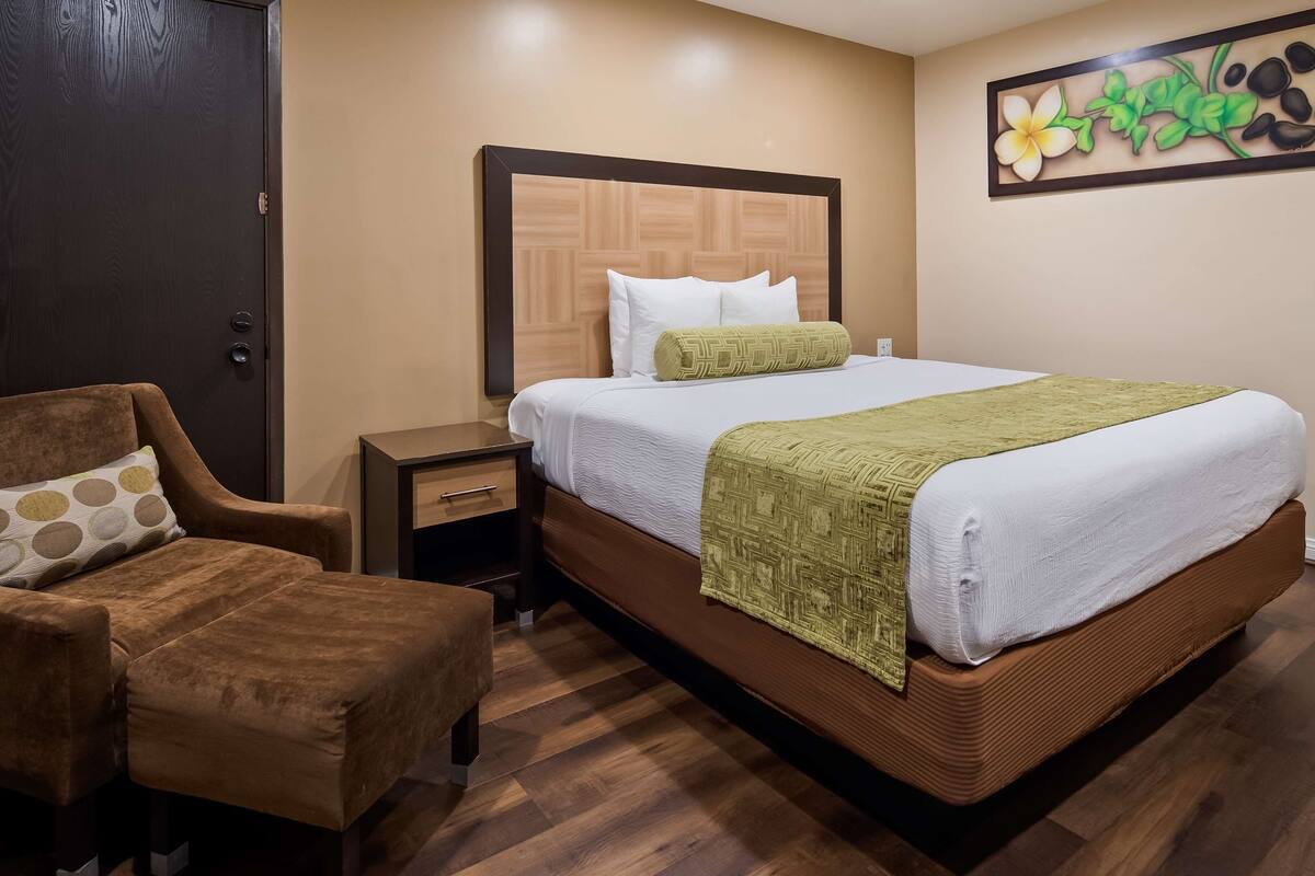 Une chambre d’hôtel avec un lit, une chaise, une table de chevet et une porte.