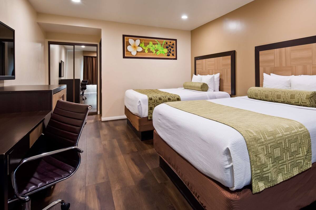 Une chambre d’hôtel avec deux lits, un bureau et une chaise.