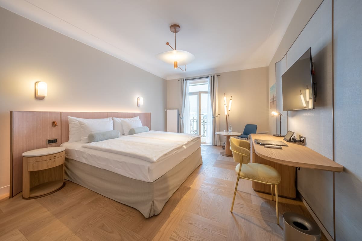 Een moderne hotelkamer met een groot bed, een bureau, een stoel, een televisie en een badkamer.
