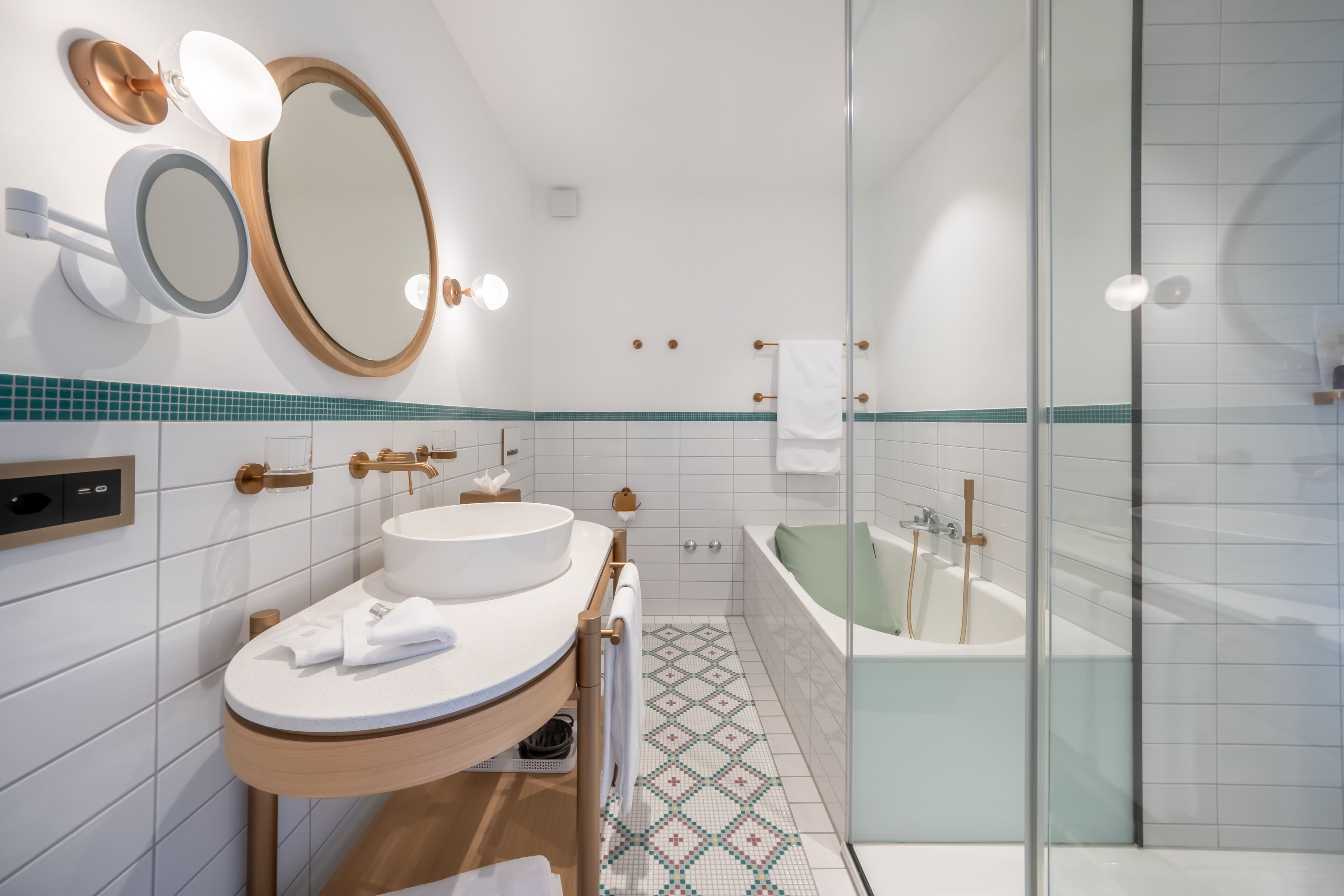 A modern bathroom with a round sink, two mirrors, a bathtub, and a shower.
