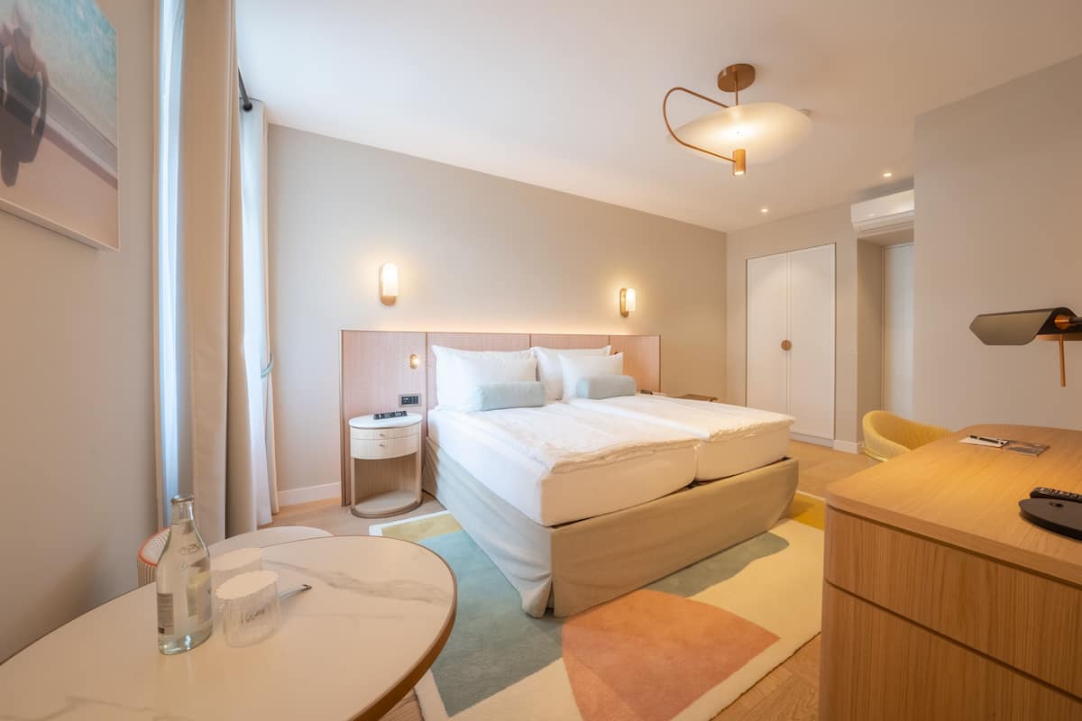 Een moderne hotelkamer met een groot bed, nachtkastjes, een bureau en een stoel.