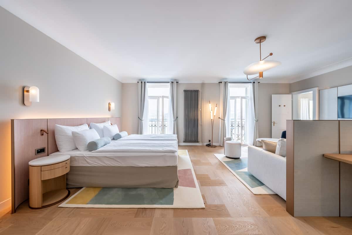 Een moderne hotelkamer met een groot bed, nachtkastjes, een bank en een spiegel.