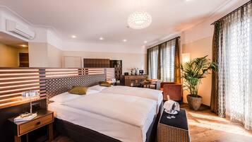 Une chambre d’hôtel moderne avec un grand lit, des tables de chevet, un bureau et une plante en pot.