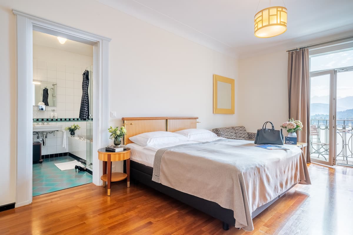 Een hotelkamer met een bed, nachtkastje en uitzicht op de omgeving.