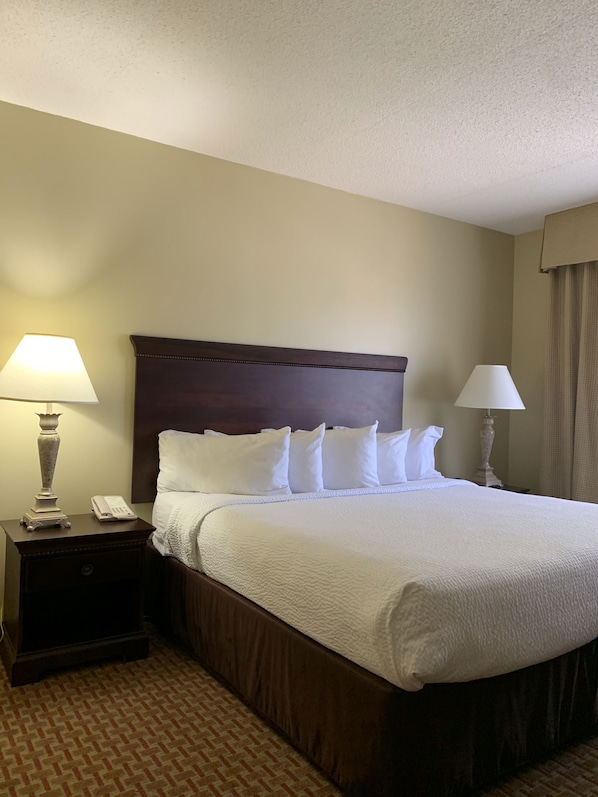 Una habitación de hotel con una cama grande, dos mesitas de noche y una mesilla.