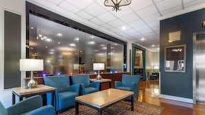 Een hotellobby met blauwe zitplaatsen, een bijzettafeltje en een getextureerd vloerkleed.