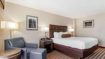 A hotel room with a bed, a desk, a chair, and two lamps.