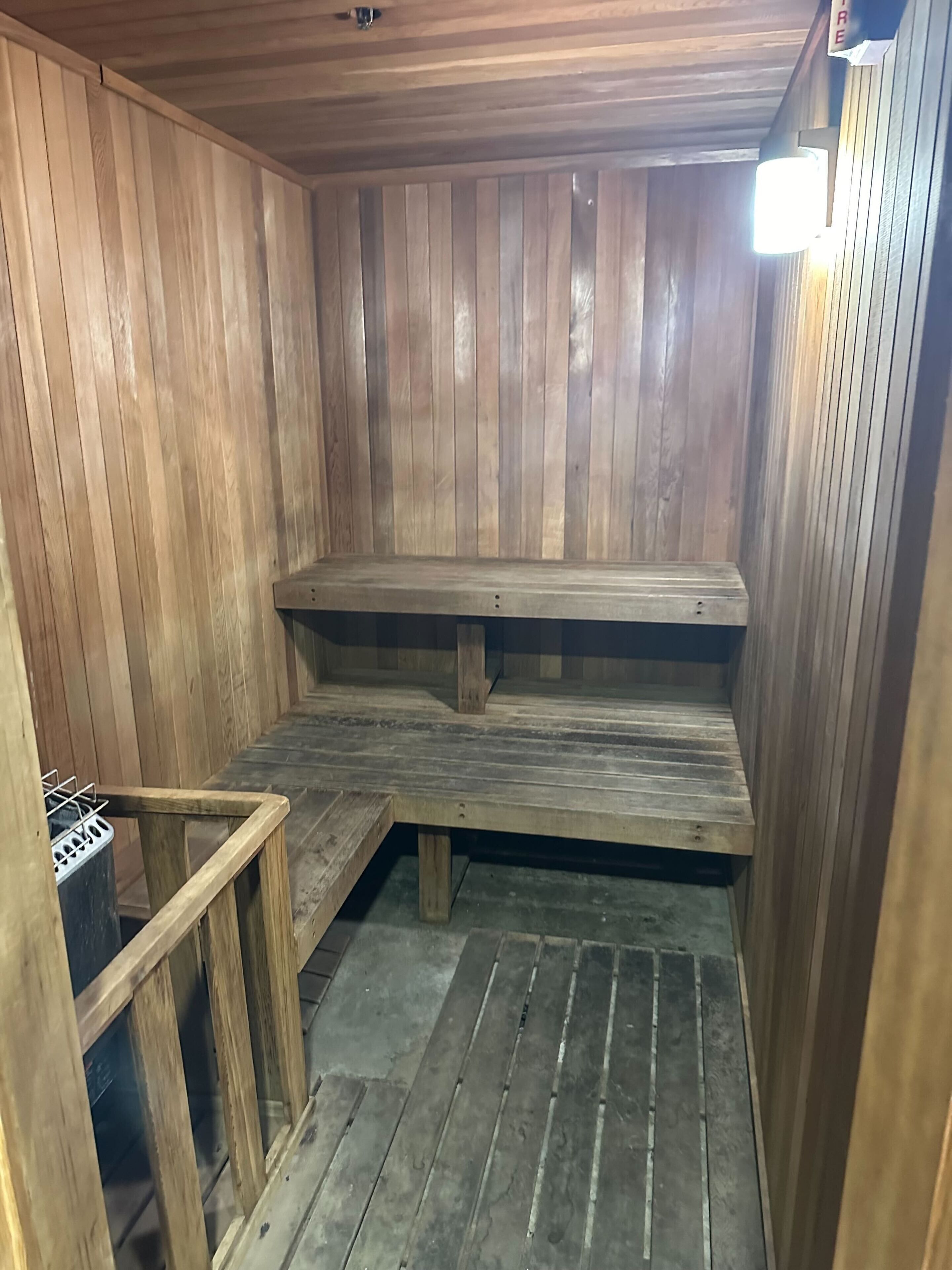 Una sauna de madera con bancos y un banco en el suelo.