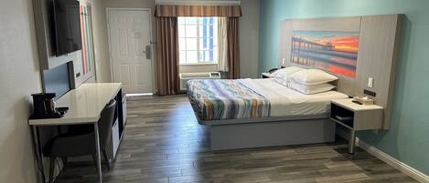 Une chambre d’hôtel avec un lit, un bureau, une chaise, une télévision et un tableau au mur.