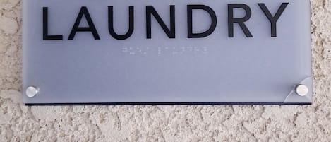 Un letrero que dice 'GUEST LAUNDRY' fijado en una pared con textura.