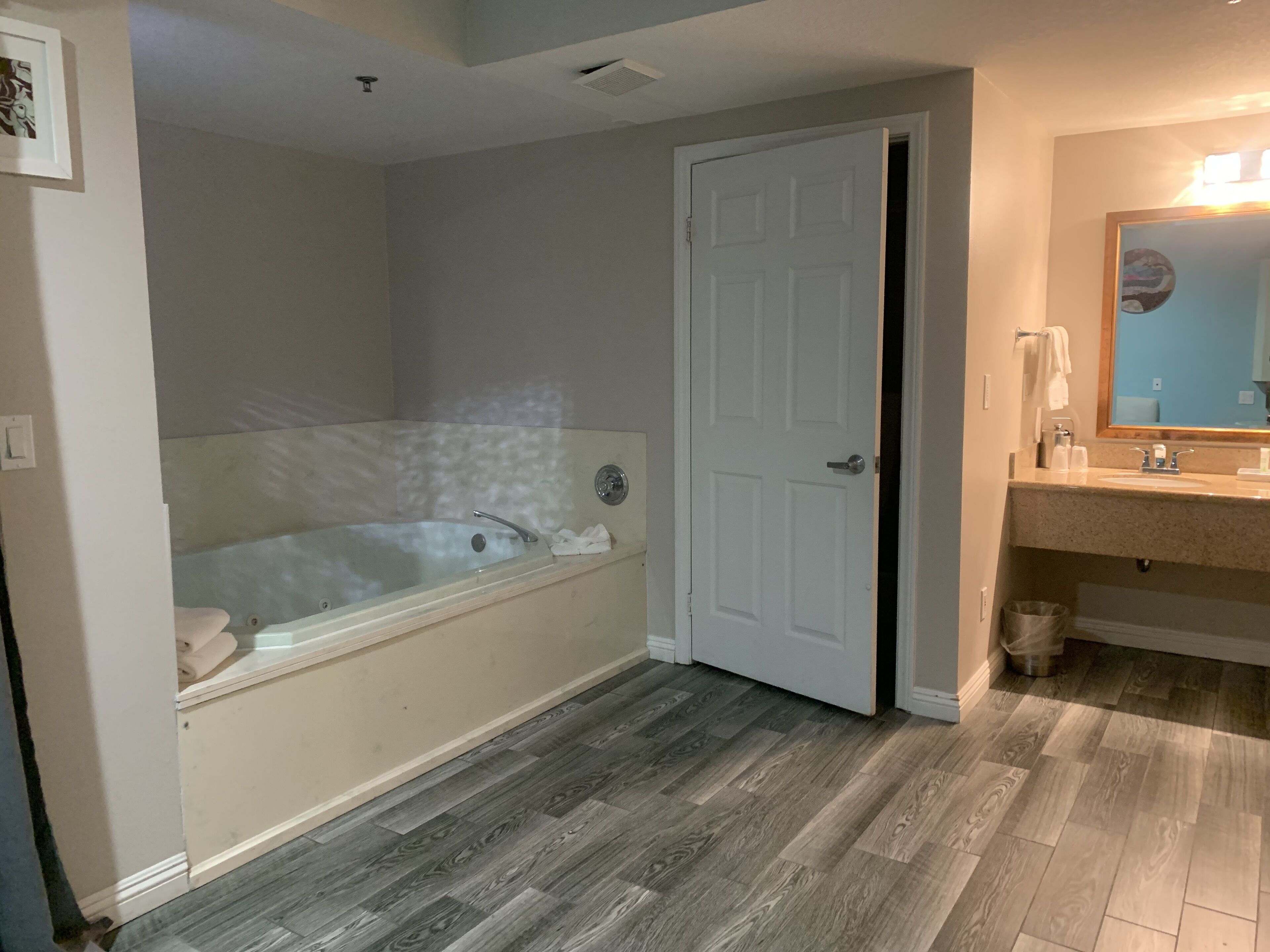 Un baño con bañera, una puerta, un lavabo y un espejo.