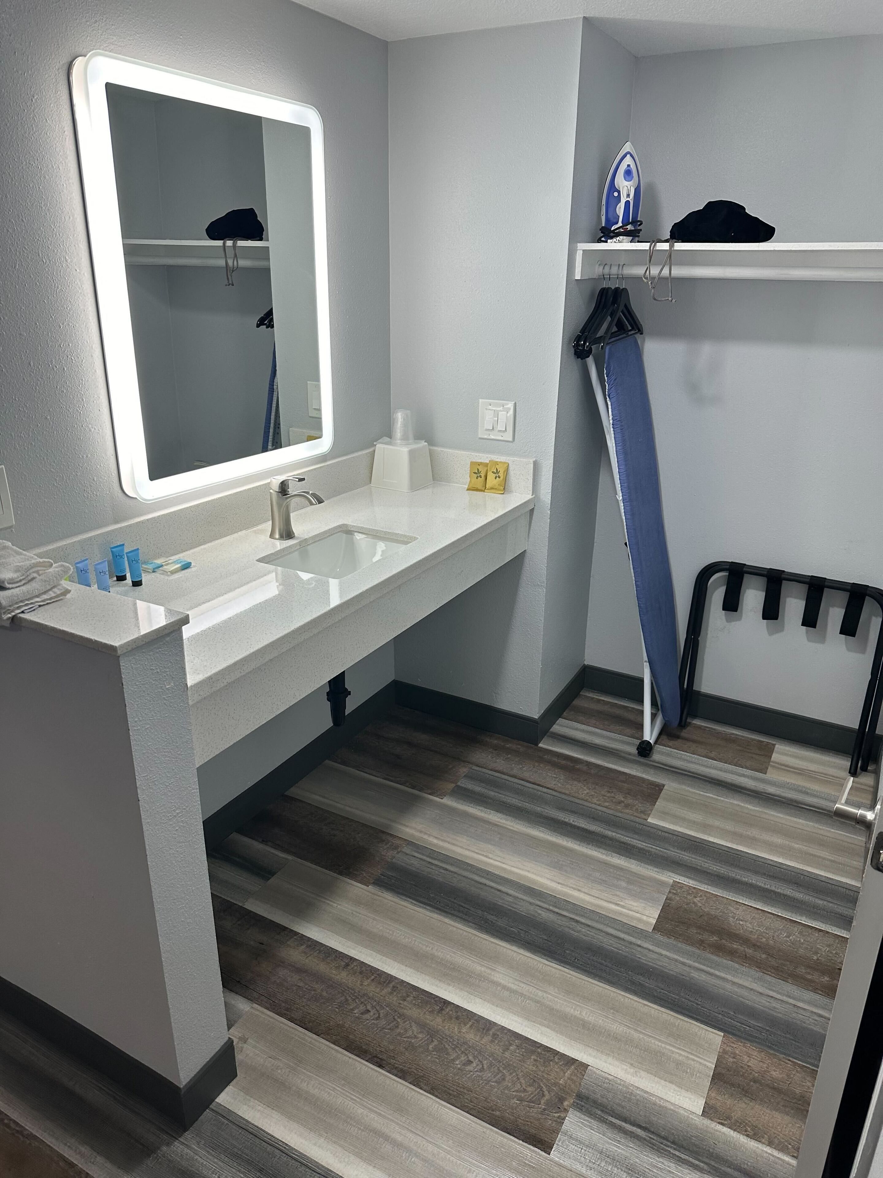 A modern bathroom with a large mirror, white sink, and a shower area.