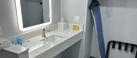 Un baño moderno con un espejo grande, lavamanos blanco y zona de ducha.