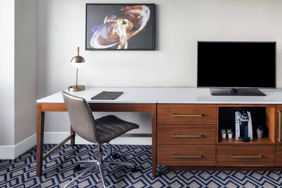 A modern office desk with a computer, a lamp, and a coffee maker.