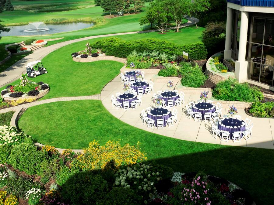 A golf course with a clubhouse, outdoor seating area, and landscaped gardens.