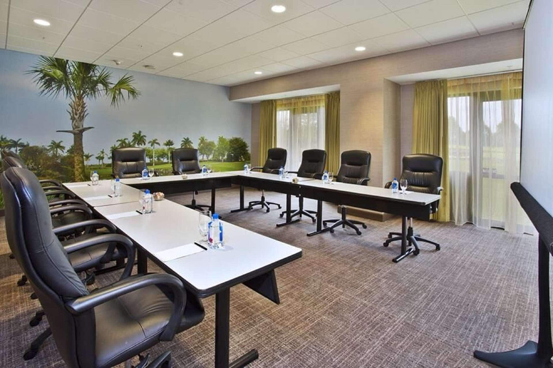 Un salón de conferencias con una larga mesa, varias sillas y piso alfombrado.