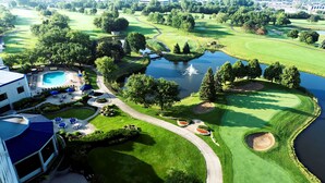 Ein Golfplatz mit Schwimmbad, Liegebereich und Teich.