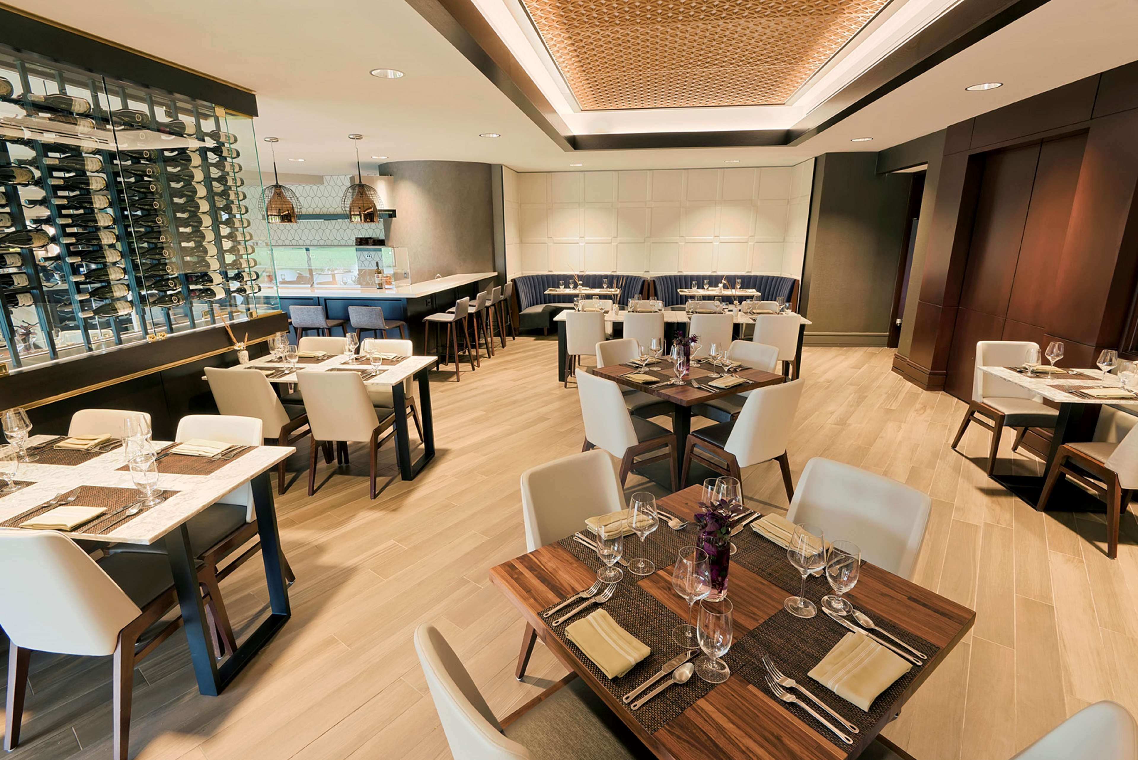 A modern restaurant with multiple dining areas, a wine rack, and a bar.
