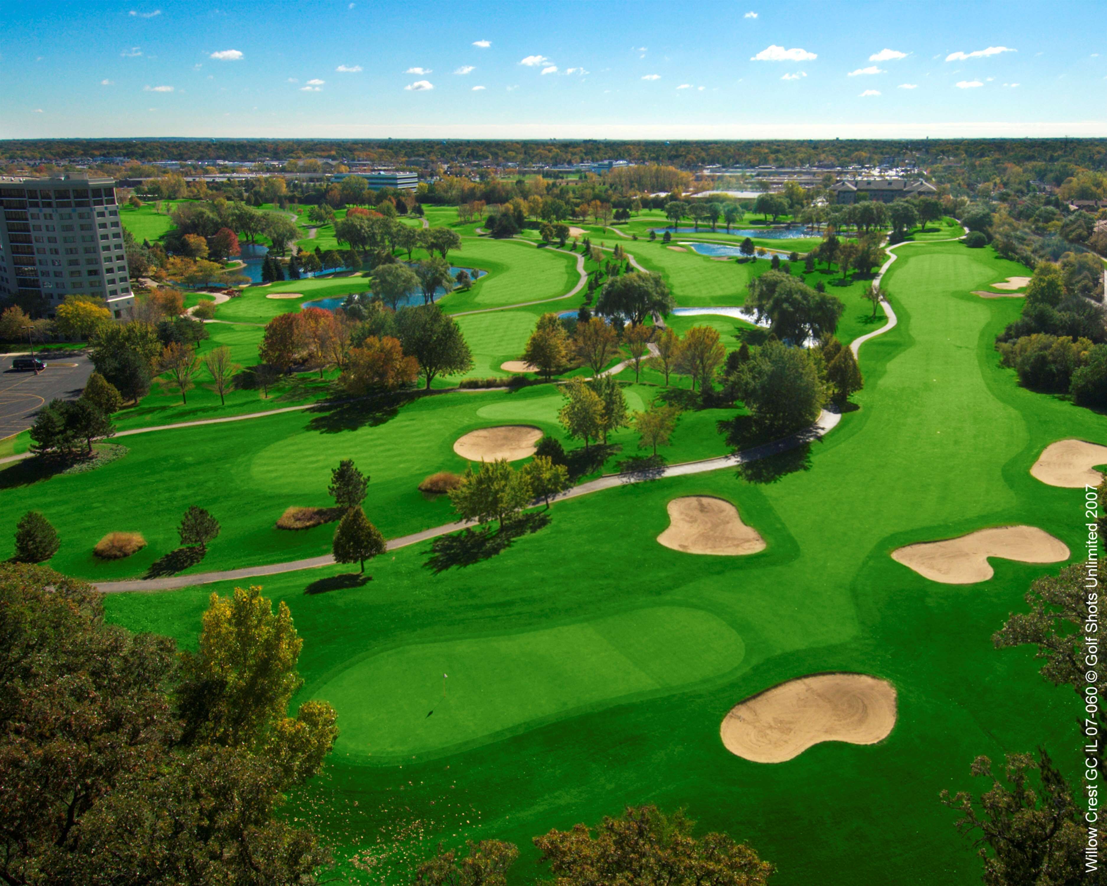 A golf course with multiple bunkers and a pond.