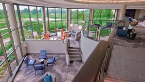 A spacious, modern interior with large windows offering views of a golf course and a lake. - Hilton Chicago/Oak Brook Hills Resort & Conference Center (Oak Brook)