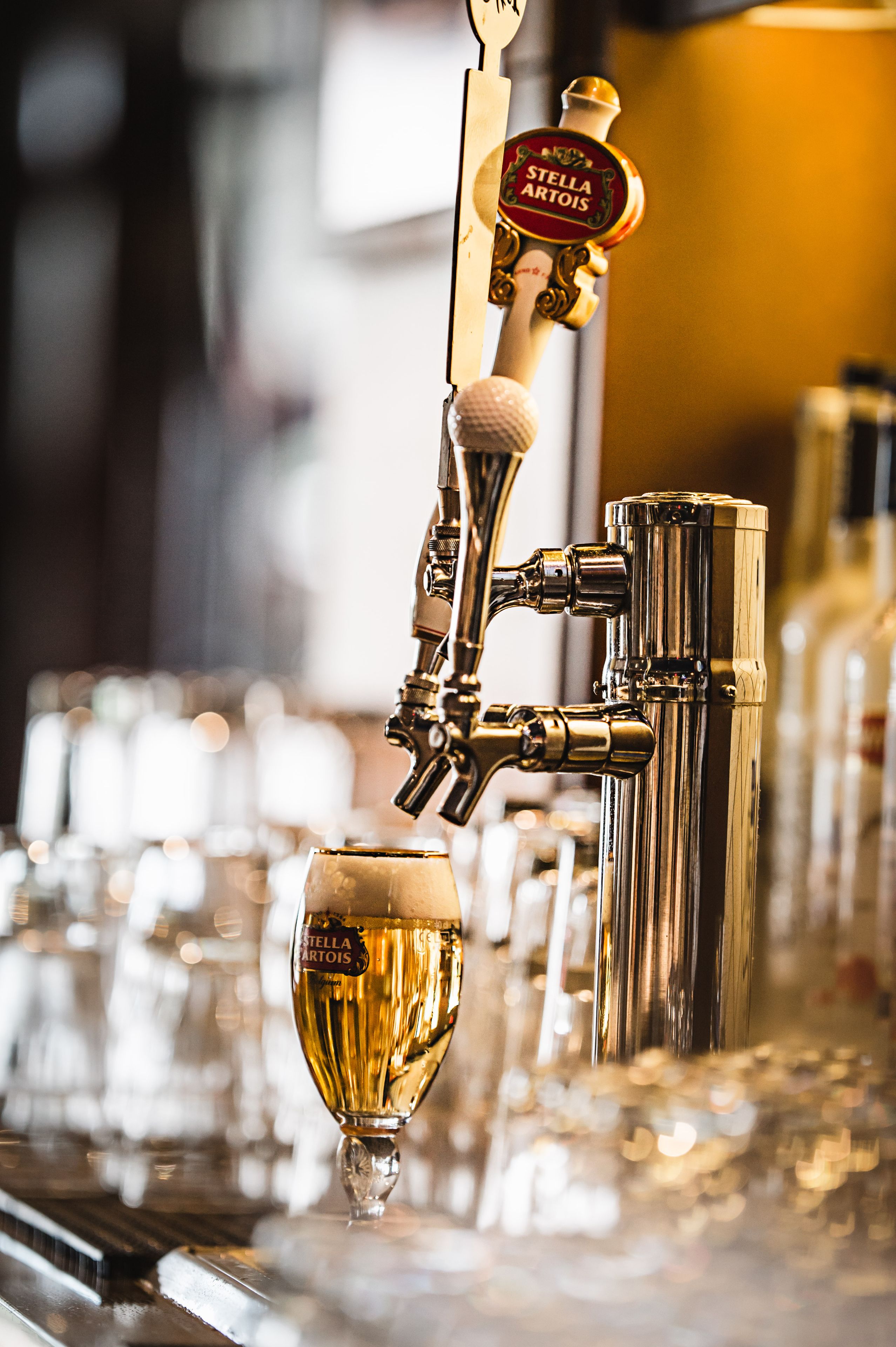 A bar tap with a beer glass being filled.