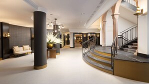 A spacious lobby with a central column, a staircase, and a sofa. - Hilton Heidelberg (Heidelberg)