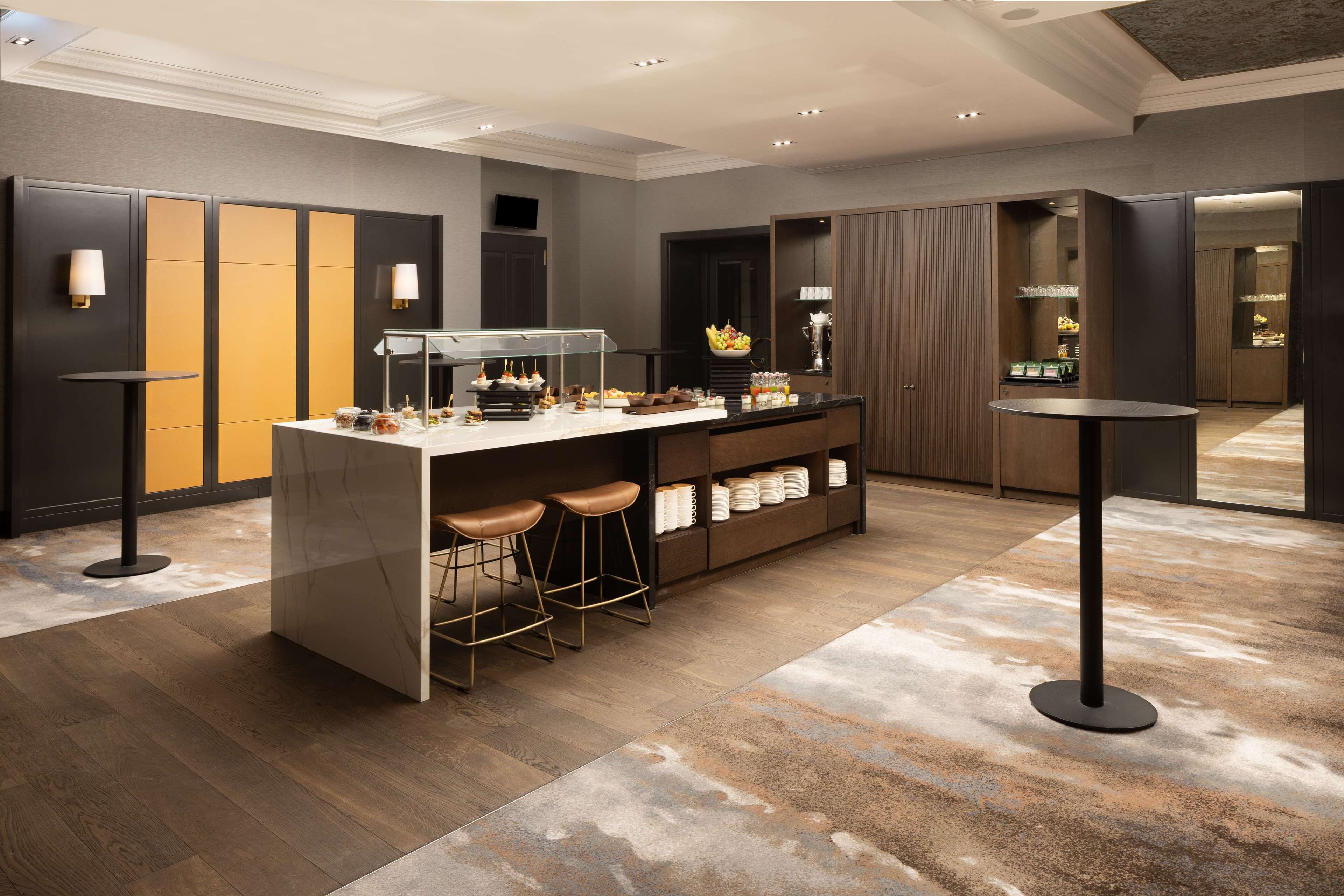 Un área de bar moderna con taburetes, mostrador y vitrina.