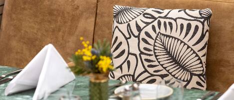 Una mesa de comedor dispuesta con servilletas blancas, una copa de vidrio transparente, un salero y un jarrón con flores amarillas.