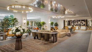 Un vestíbulo amplio con zona de comedor central, disposición de asientos y mostrador de recepción.