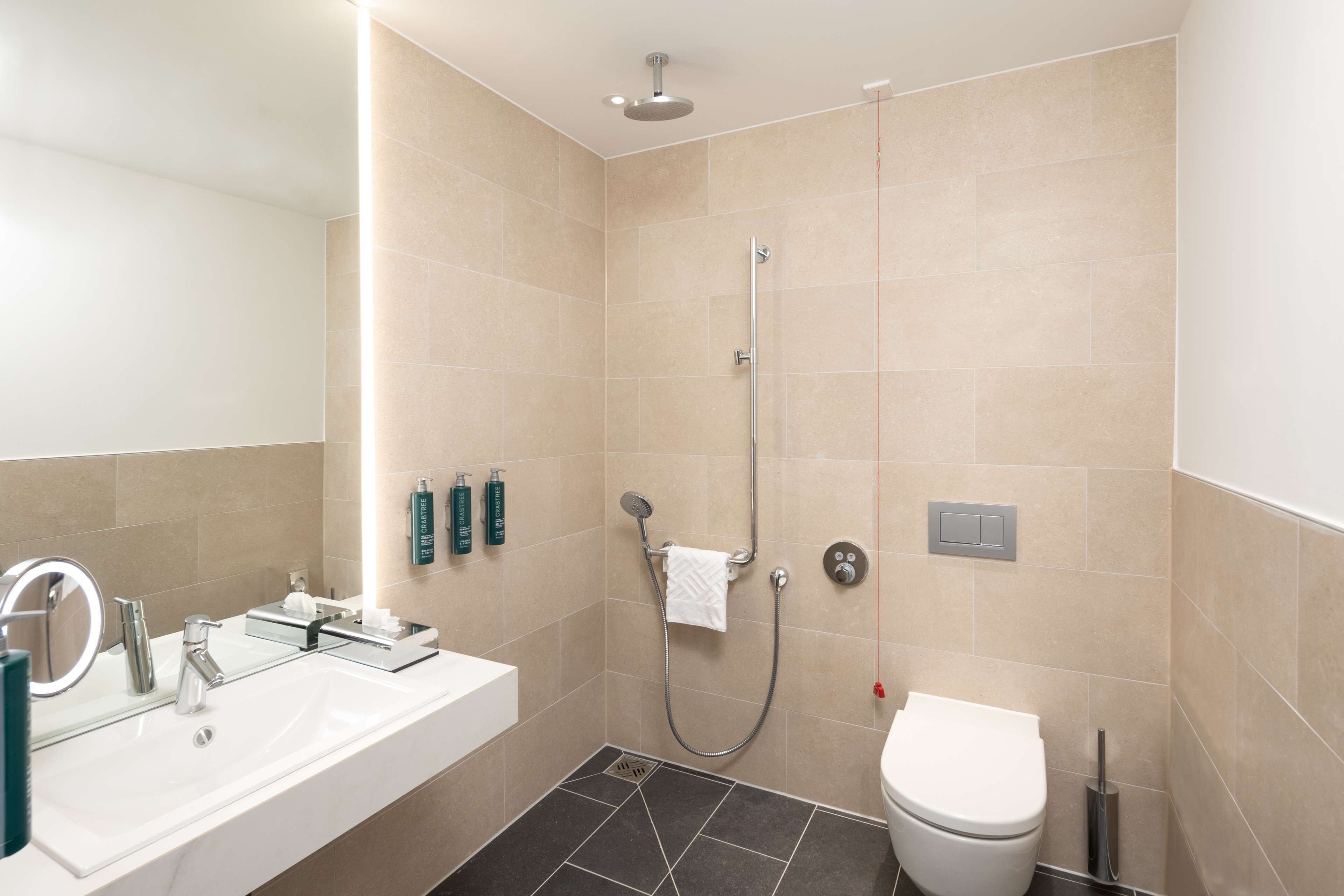 Un baño moderno con lavamanos, espejo y retrete blancos.