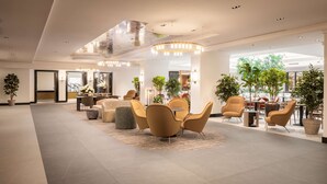 A spacious lobby with modern furniture, large windows, and indoor plants. - Hilton Heidelberg (Heidelberg)
