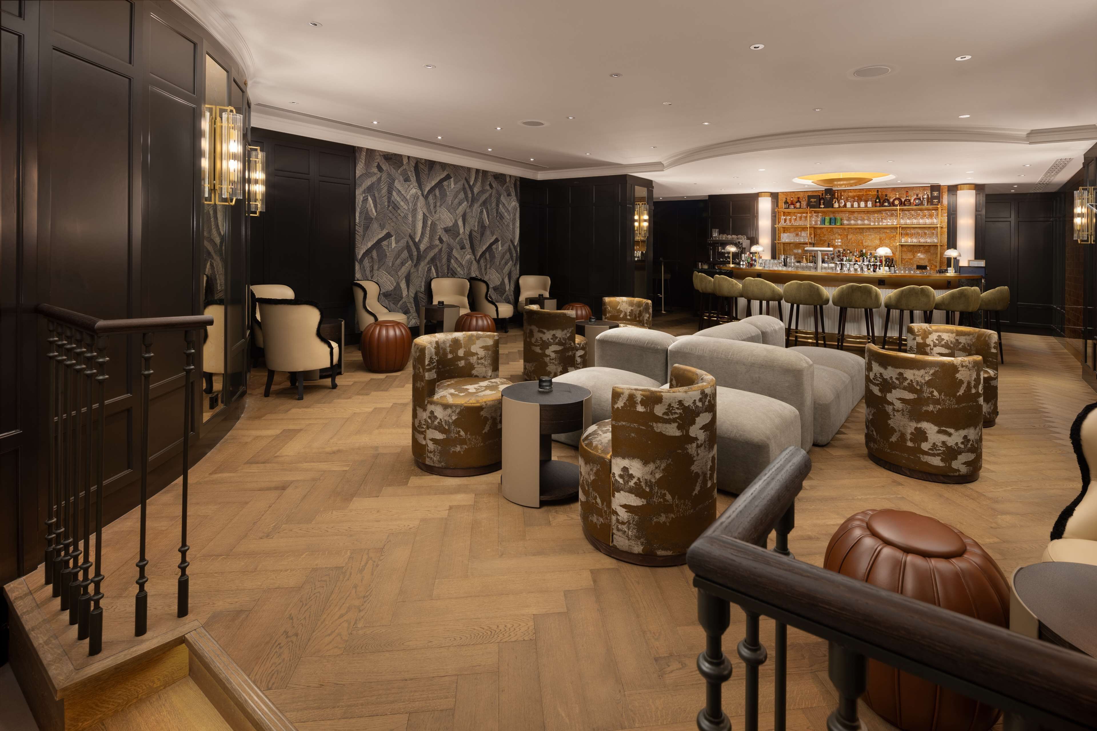 A spacious lounge area with multiple seating options, a bar, and a staircase leading to an upper floor.