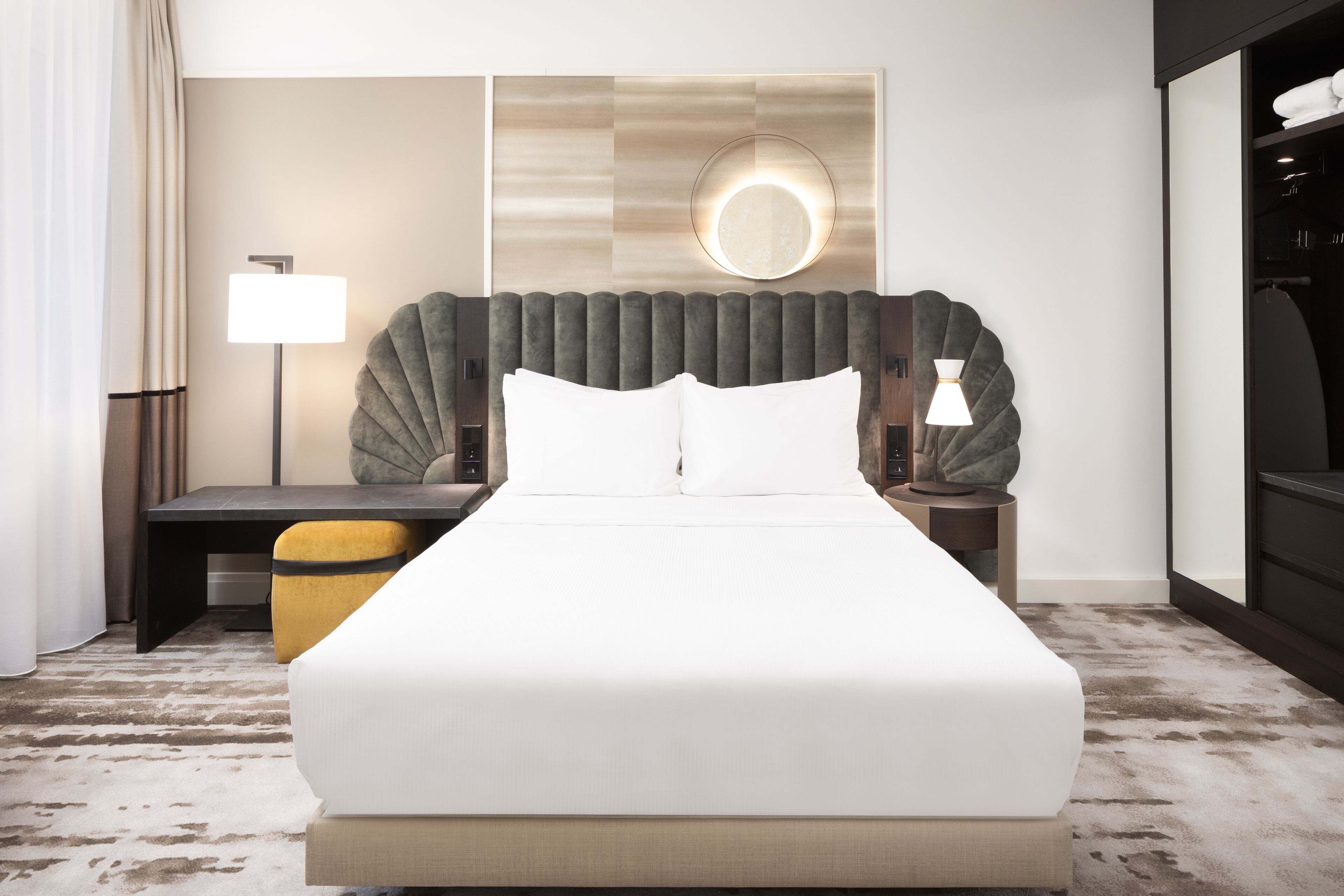 Ein modernes Hotelzimmer mit einem großen Bett, einem Nachttisch, einer Lampe und einem Spiegel an der Wand.