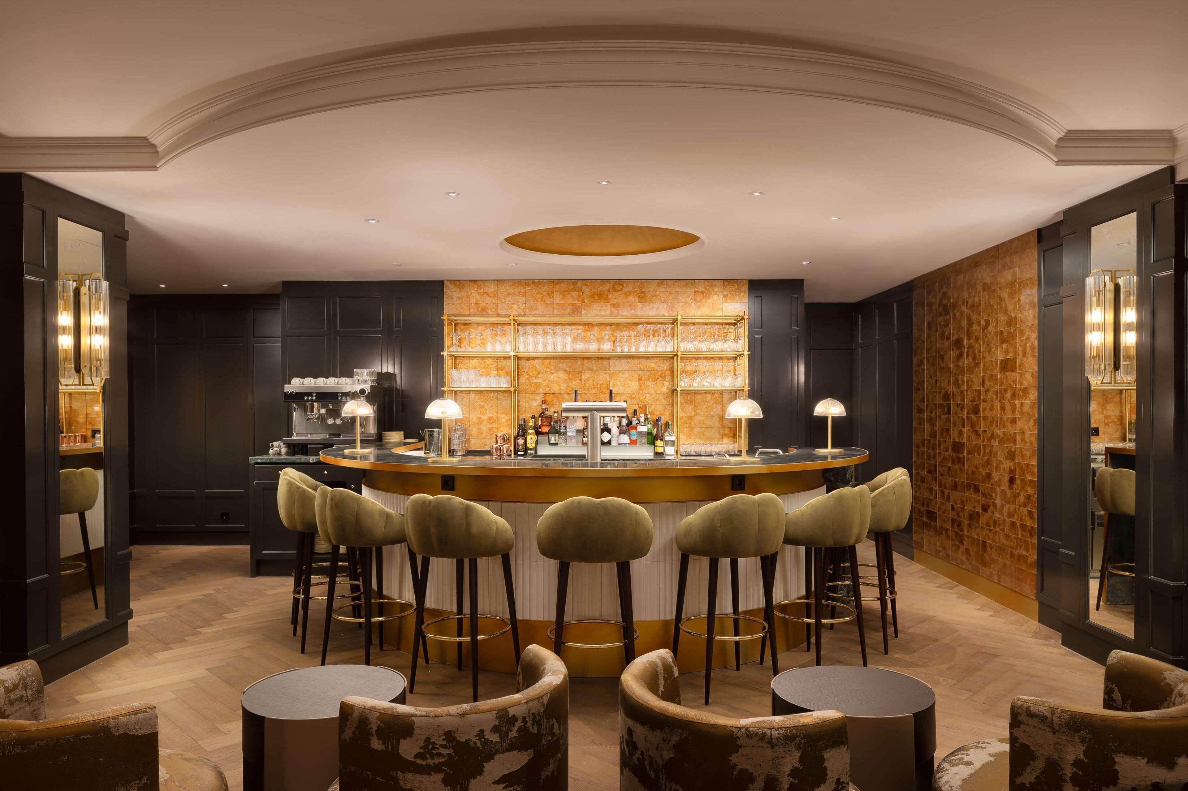 A bar area with a central counter, bar stools, and a seating area with round tables and chairs.