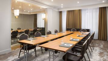 Une salle de conférence avec une longue table, des chaises et un grand miroir.