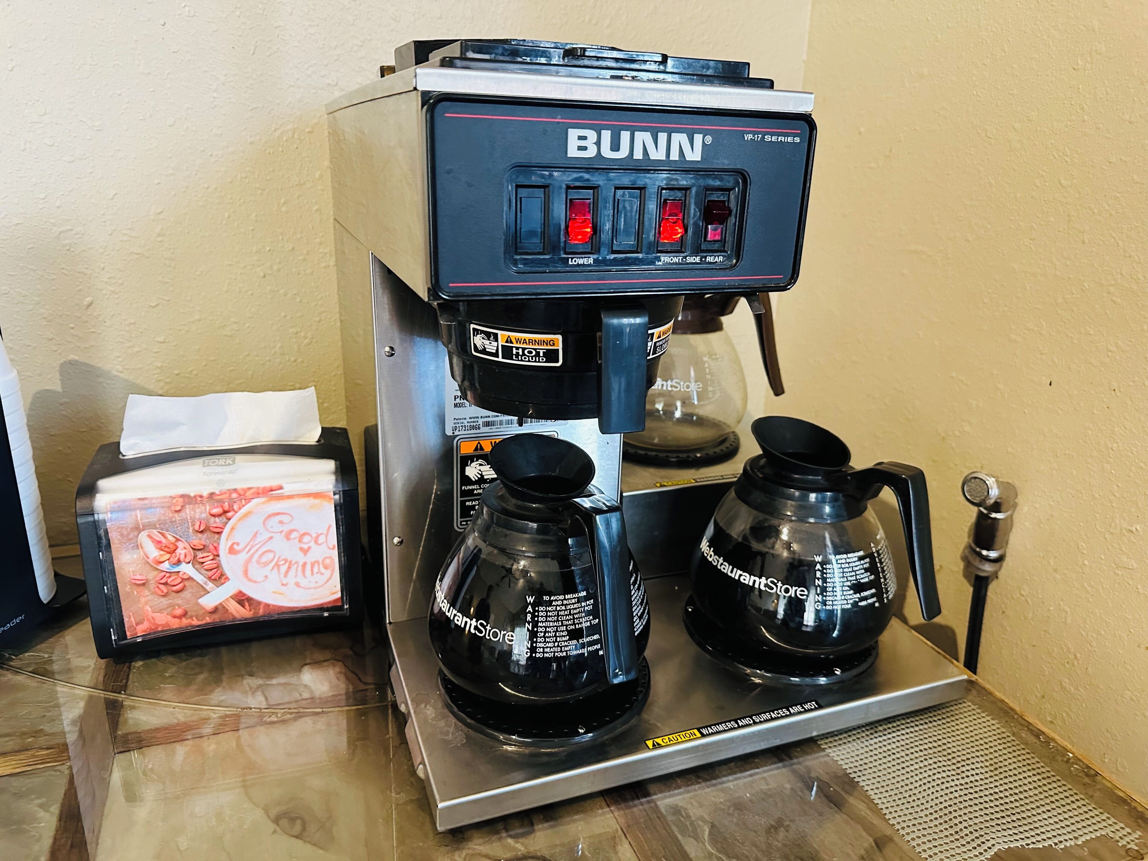 A Bunn coffee machine with two portafilters and a tissue box.