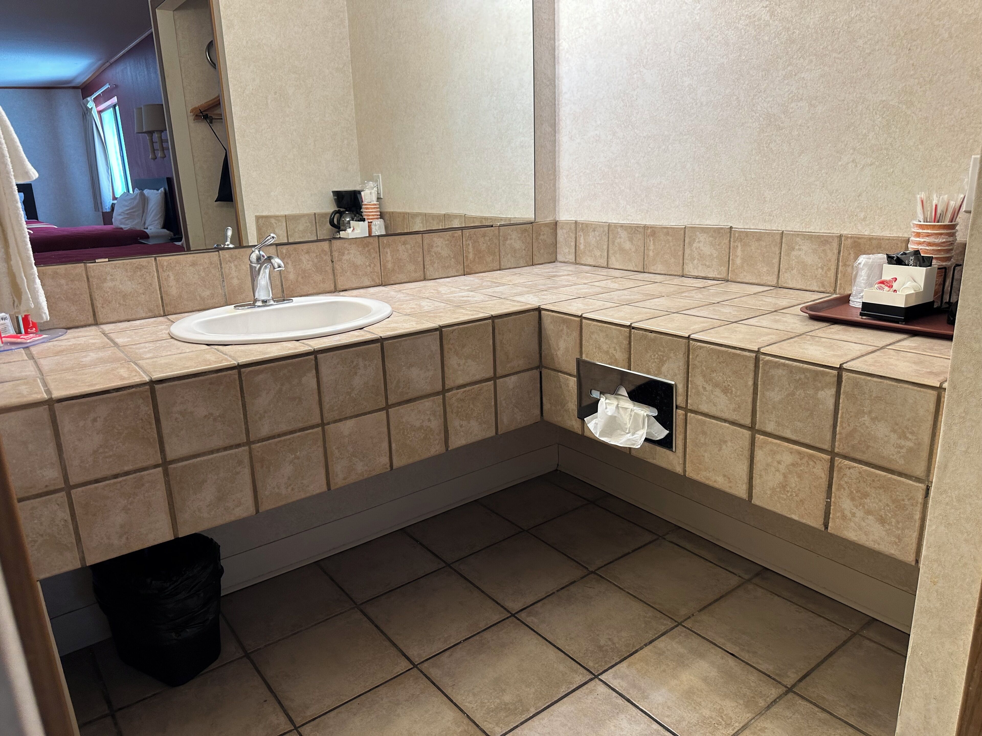 A modern bathroom with a sink, mirror, and towel dispenser.