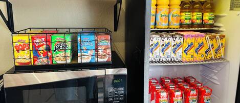 A kitchenette with a microwave, cereal, and juice cartons.