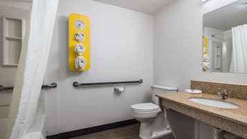 Une salle de bain équipée de toilettes, d’un lavabo et d’un distributeur de serviettes fixé au mur.