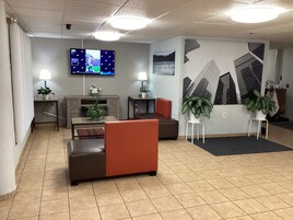 Un hall con zona de estar, televisor montado en la pared y un mural grande.