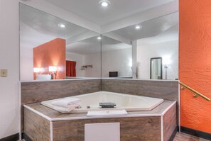 Un baño moderno con un espejo grande, una bañera y un tocador de madera.
