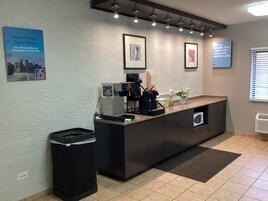 Un área de recepción moderna con una máquina de café, un cubo de basura y obras de arte enmarcadas en la pared.