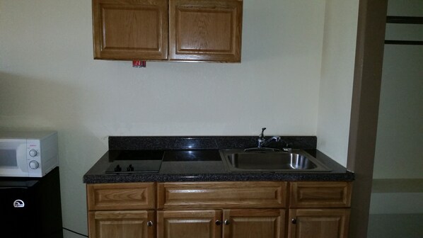 A kitchen with wooden cabinets, a stainless steel sink, and a microwave.