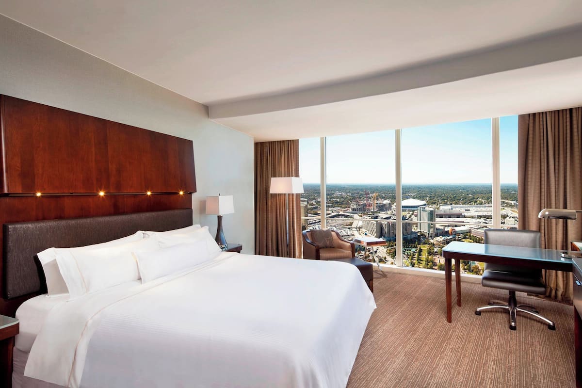 Een hotelkamer met een groot bed, een bureau en uitzicht op een stadsgezicht.