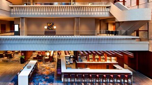 A hotel lobby with a bar area, seating, and a staircase connecting floors.